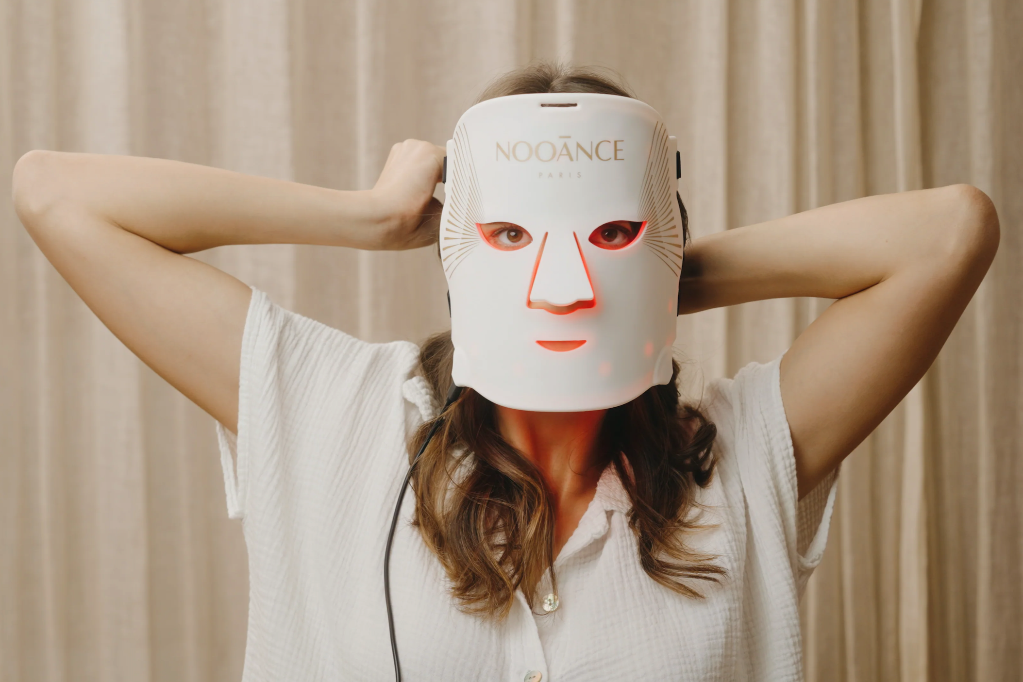 Woman wearing Nooance LED face mask at home during red light therapy treatment