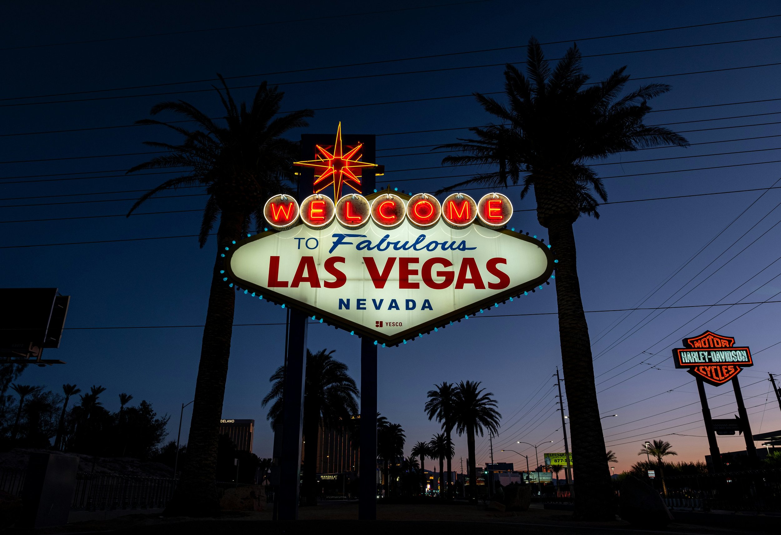 Welcome to Fabulous Las Vegas sign at dusk with palm trees and city lights