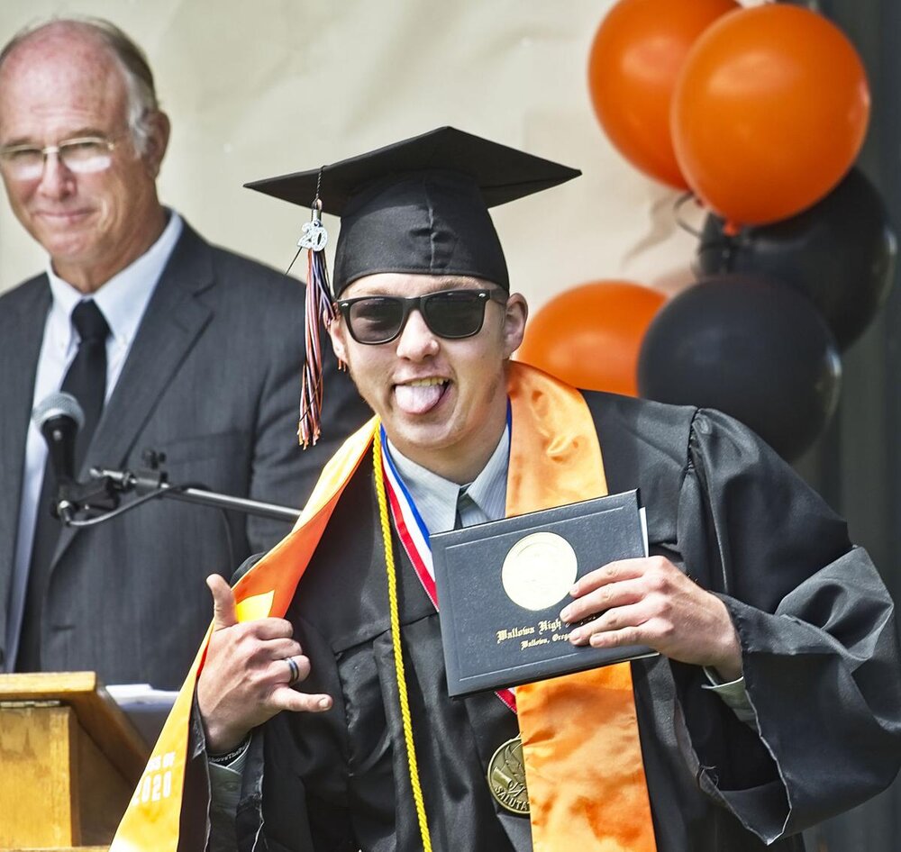  Salutorian Quentin Tillery celebrates his diploma  as a bemused Jay Hummel looks on.  