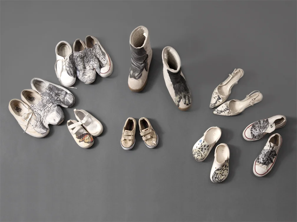 Walk in Their Shoes Installation: varying in size Reclaimed shoes, photo transfer 2014 Displayed on the platform are Black rhinoceros’ feet on a threesome of tennis shoes, Hawksbill sea turtle flippers on sneakers, feet of Nene geese (the official bird of Hawaii) on women’s sandals, snow leopard’s paws on baby Crocs , a monarch butterfly and Macaya breast-spot frog on baby’s canvas loafers, and a mountain gorilla’s paws on boots. These are some of the animals on the critically endangered animal list that need our ardent advocacy for their habitat conservation and anti-poaching enforcement.