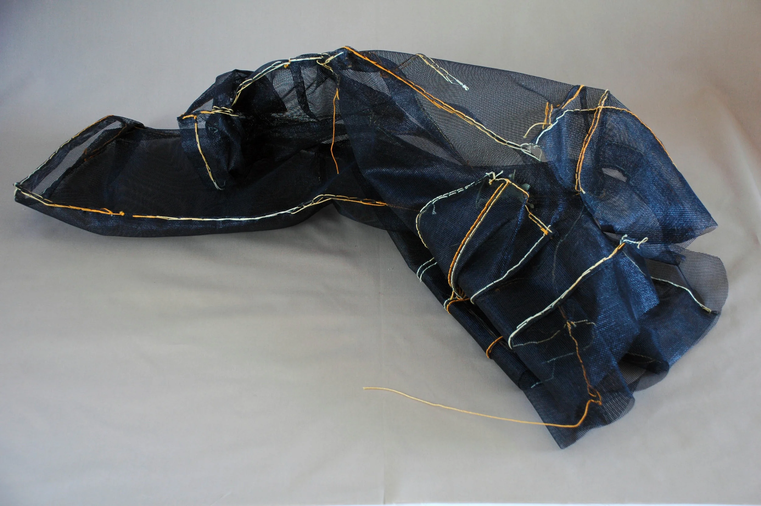 Growing Overnight: Each year the drawers would fill with outgrown jeans of our three boys. Like butterflies casting their cocoons, they were reminder of the boy's impending metamorphosis to adulthood. 2"h x24"w x6"d Window screen, threads 2009