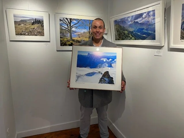   Ty Mitchell of eXp Realty, Newbury Street, Boston, with Jeffrey Trubisz’s photograph  Climber Rappelling, Aigiuille de Midi, France.   