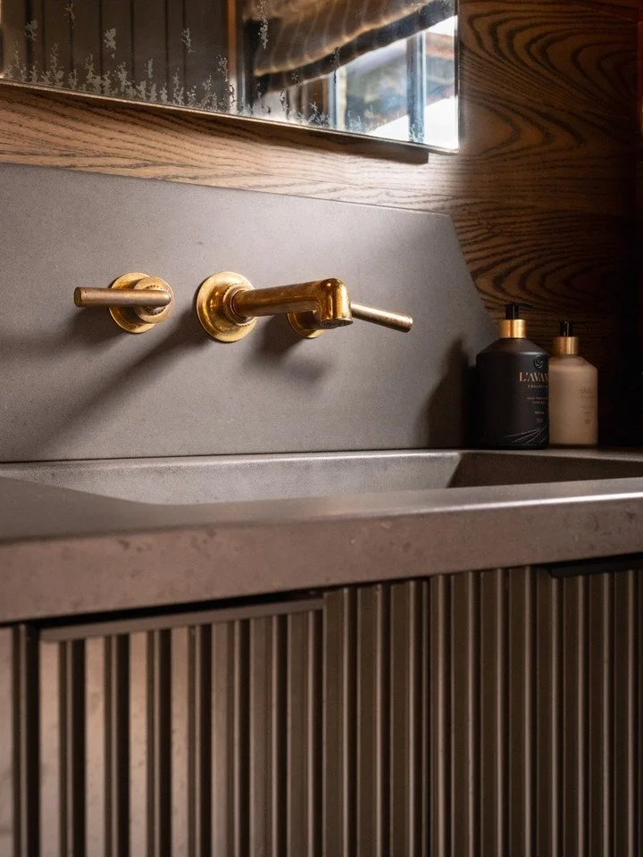 Moody by design, elevated by material. Rich wood grain, warm brass, and sculptural lines come together in a space that invites you to linger in a feeling - a feeling that you won't forget.