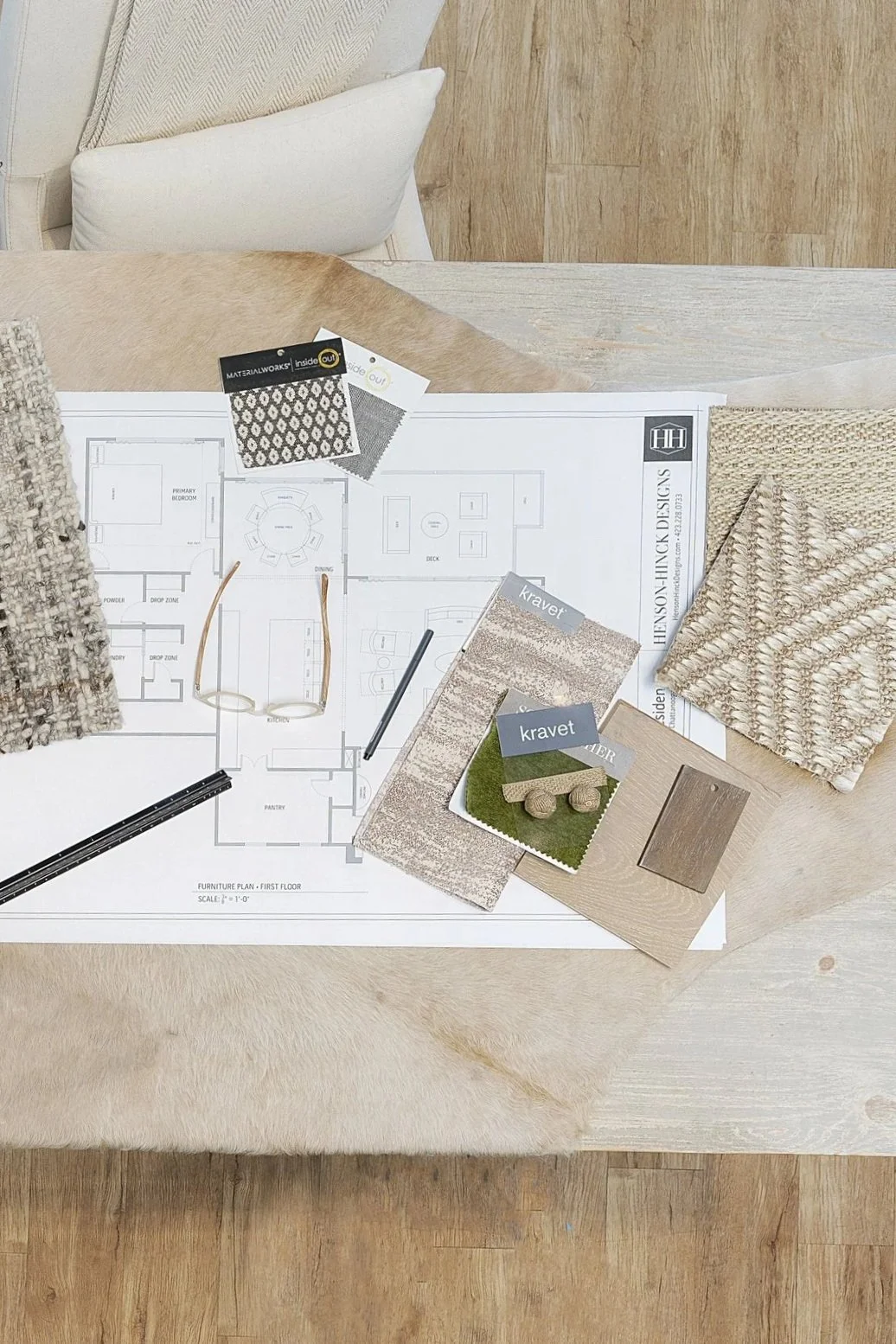 Interior design planning with fabrics, paint swatches, and a floor plan on a table.