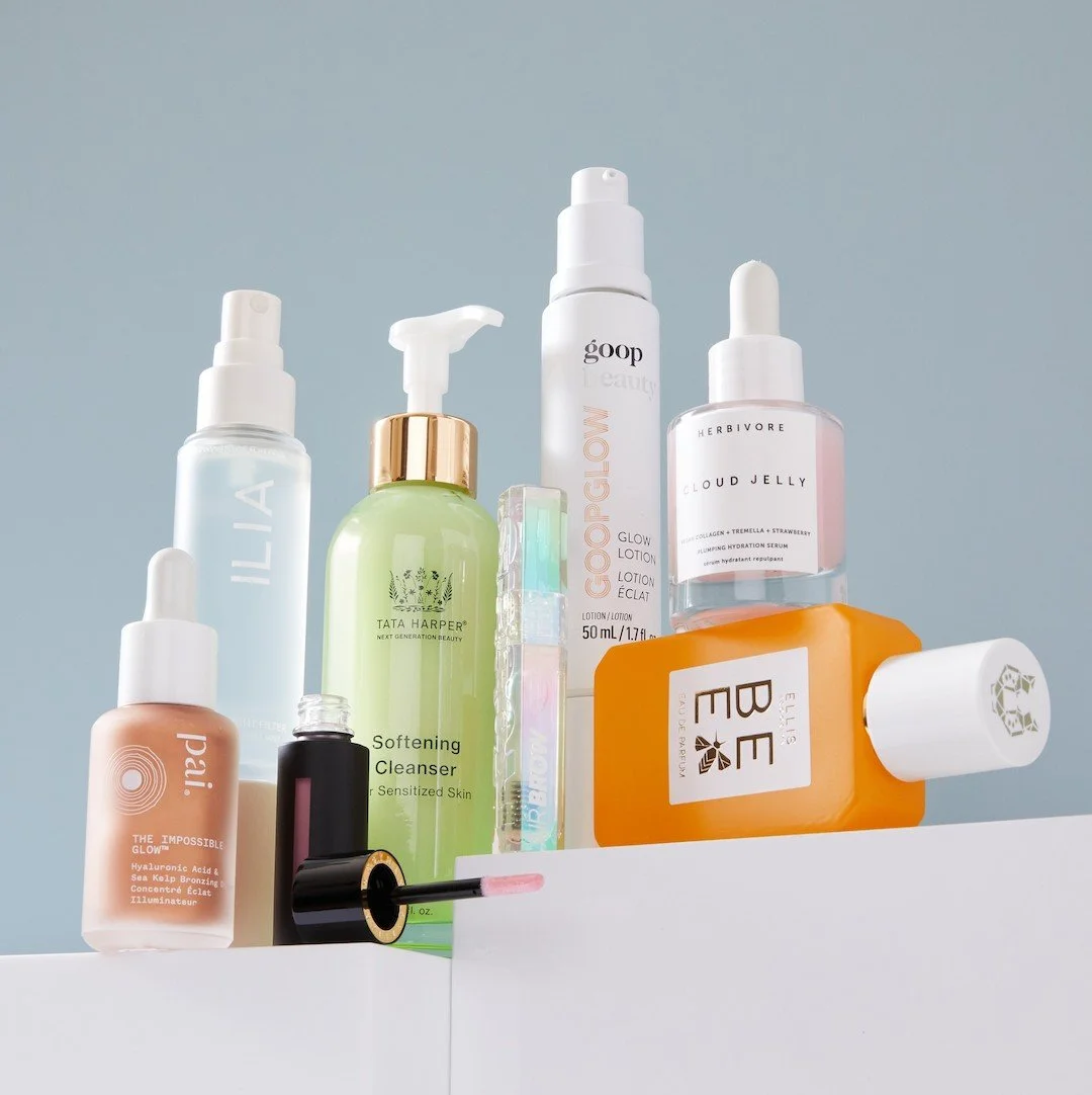 A group of bottles of various colors and shapes on a platform in front of a white background.