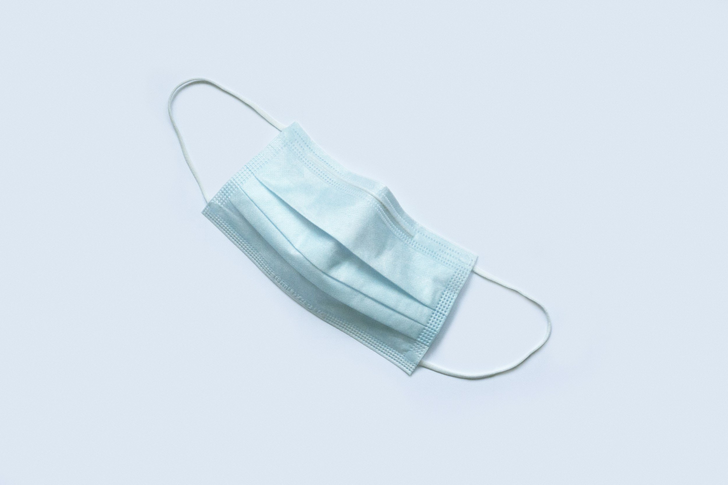 A blue medical mask on a blue background.