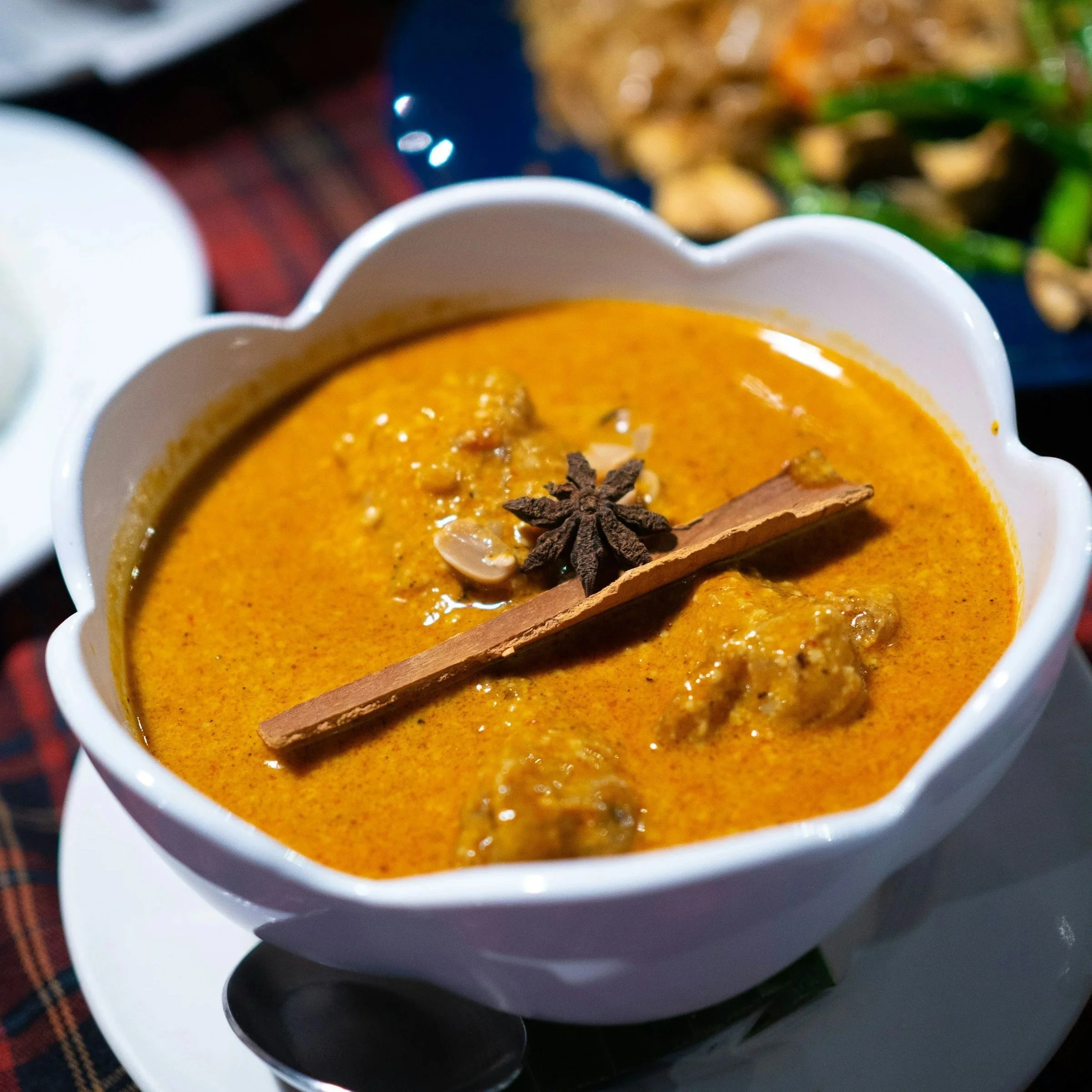 A white bowl filled with orange soup on a table with other foods.
