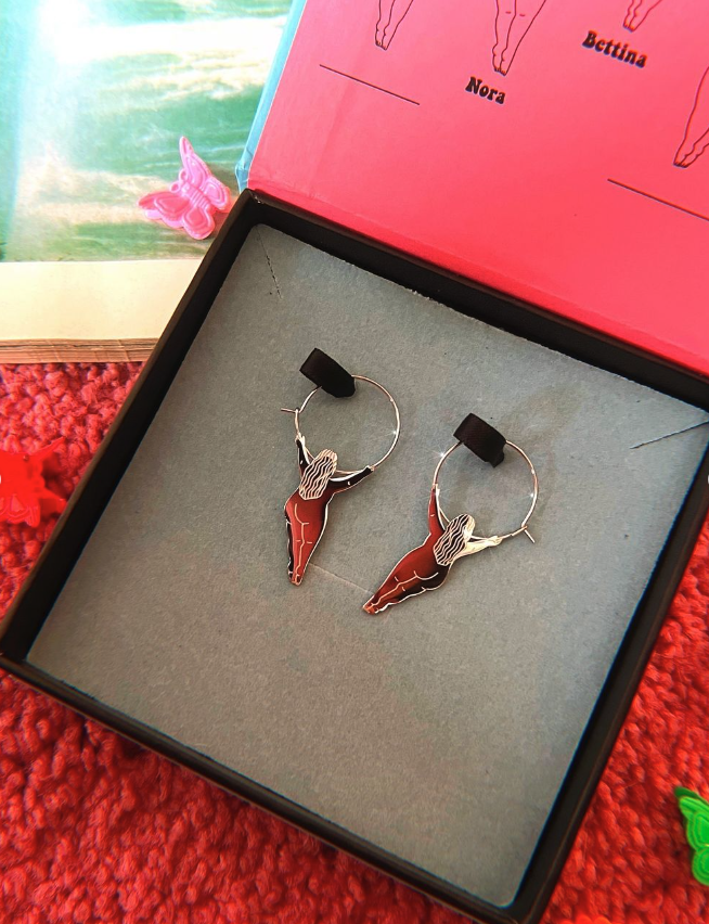 A pair of gold hoop earrings with two fat women hanging off.