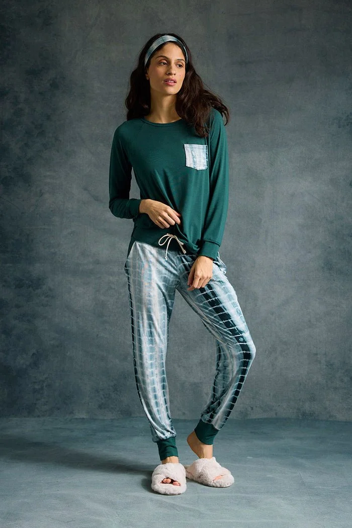 A model wears a matching bamboo pajama set with a long-sleeve top and relaxed tie-dye harem pants, showcasing comfortable, ethically made loungewear designed for everyday ease.