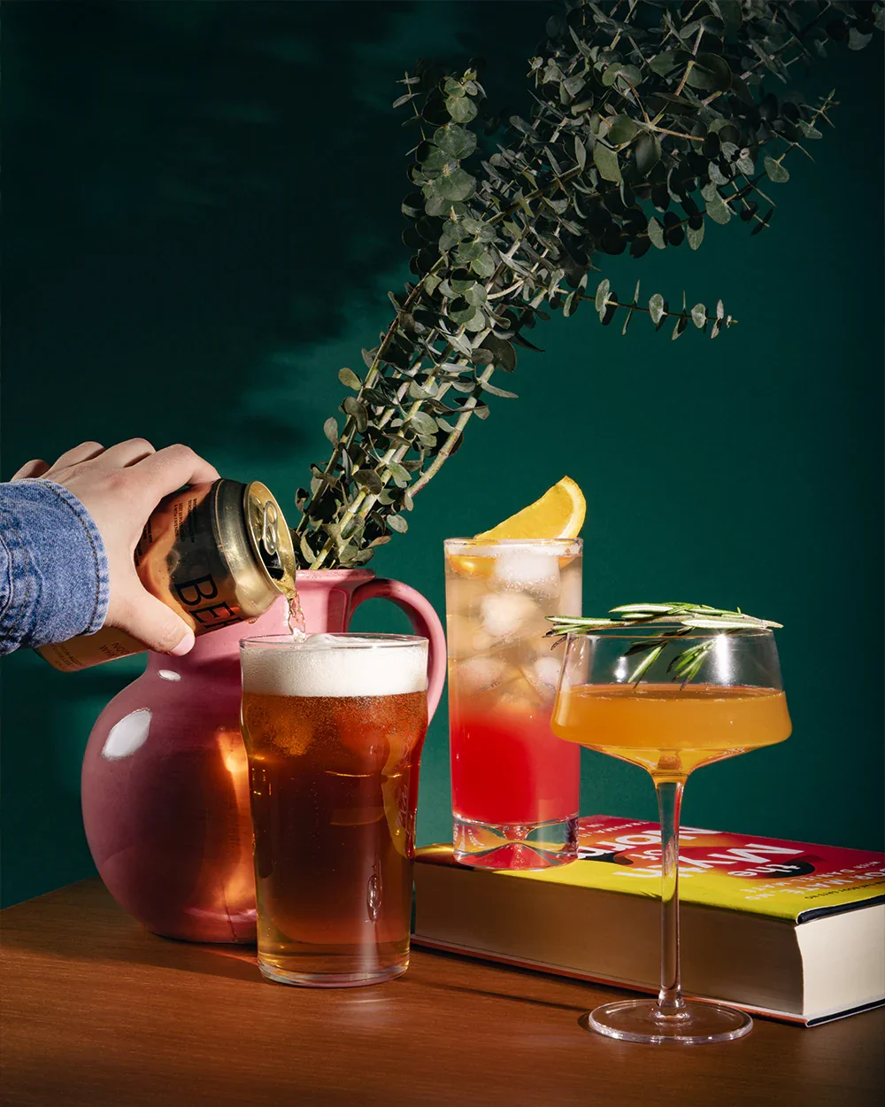 A collection of non-alcoholic cocktails and beer is styled on a table with citrus and greenery, representing elevated zero-proof drink options.