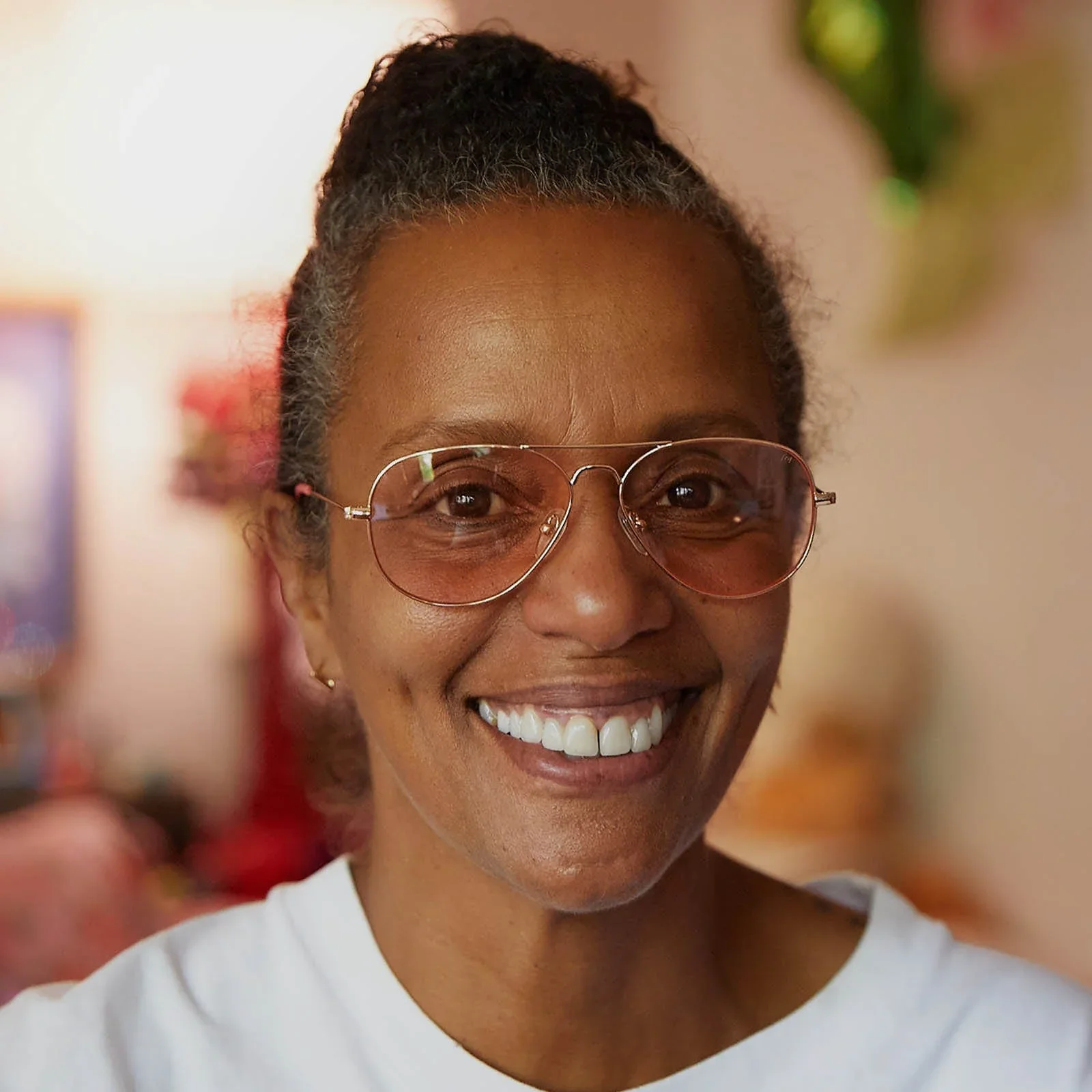 A smiling person wears stylish CADDIS reading glasses with lightly tinted lenses, highlighting the brand’s bold, age-positive approach to eyewear.