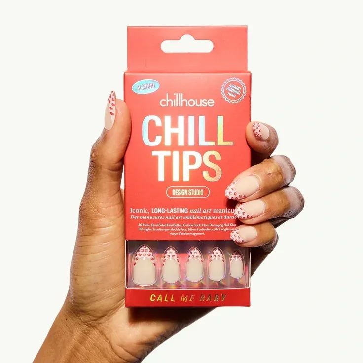 A hand holds a box of Chillhouse Chill Tips press-on nails in a red Valentine-inspired design with heart-accented nail art.
