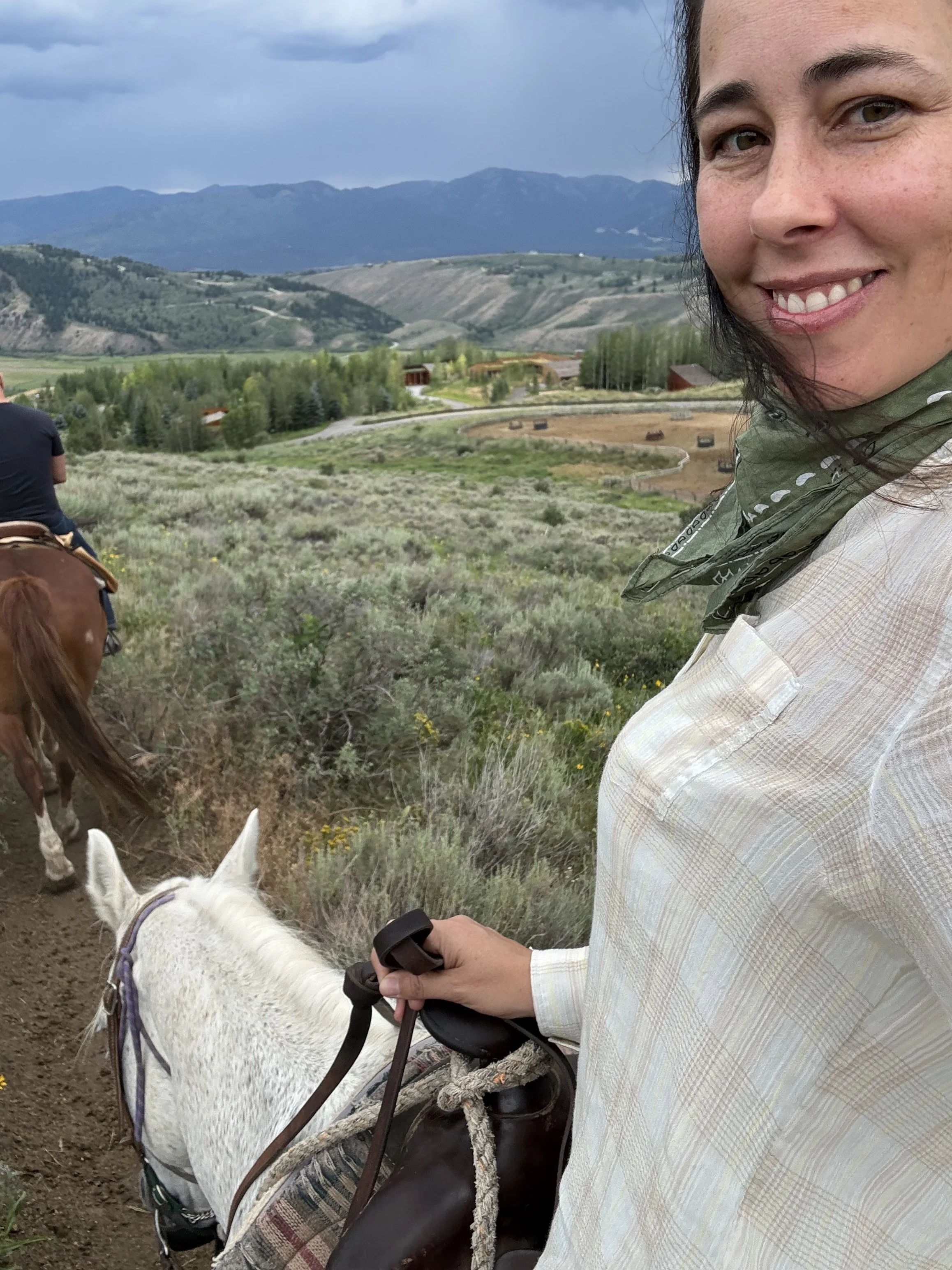 Lindsay Scott on white horse in Wyoming. The. Scott Team real estate