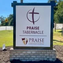 Sign for Praise Tabernacle Christian Academy featuring a cross symbol and the church's name.