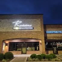 Exterior view of a building with a neon sign that says 'Relaxation' and a smaller sign that says 'Spa & Alternatives,' with a chiropractic office nearby.