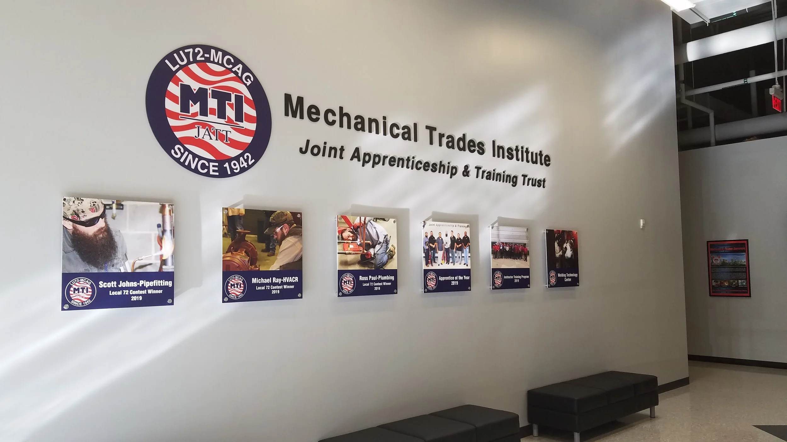 Wall display at the Mechanical Trades Institute with photos of award winners and the institute logo