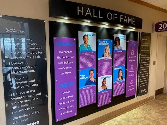 WellStar Healthcare Hall of Fame display with posters highlighting mission, vision, respect, making a difference, values, innovation, compassion, team approach, and well-being.
