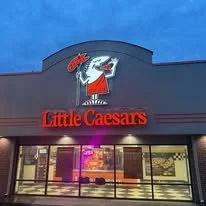 Front of Little Caesars pizza restaurant with the logo of a Roman soldier holding a pizza cake on a blue sky background.