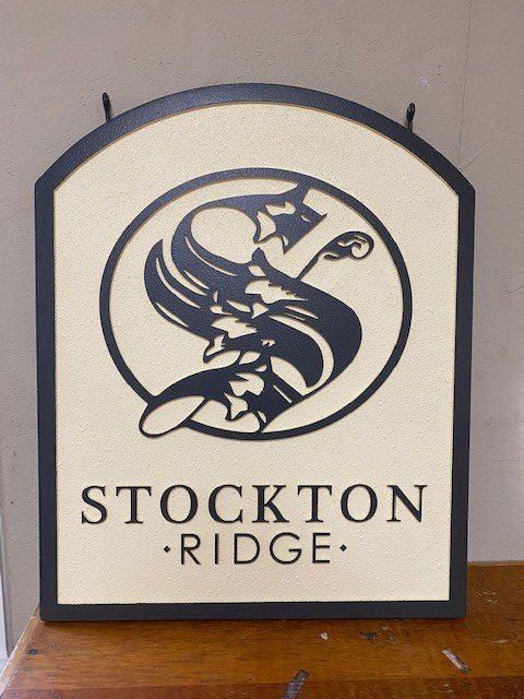 A sign for Stockton Ridge featuring a stylized eagle with wings spread and clutching a scepter, enclosed in a circle, with the text 'Stockton Ridge' below.