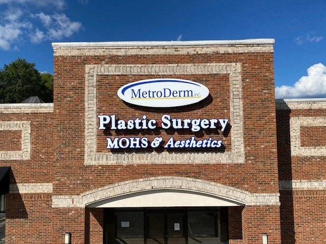 Brick building with signs for MetroDerm, plastic surgery, MOHS, and aesthetics.