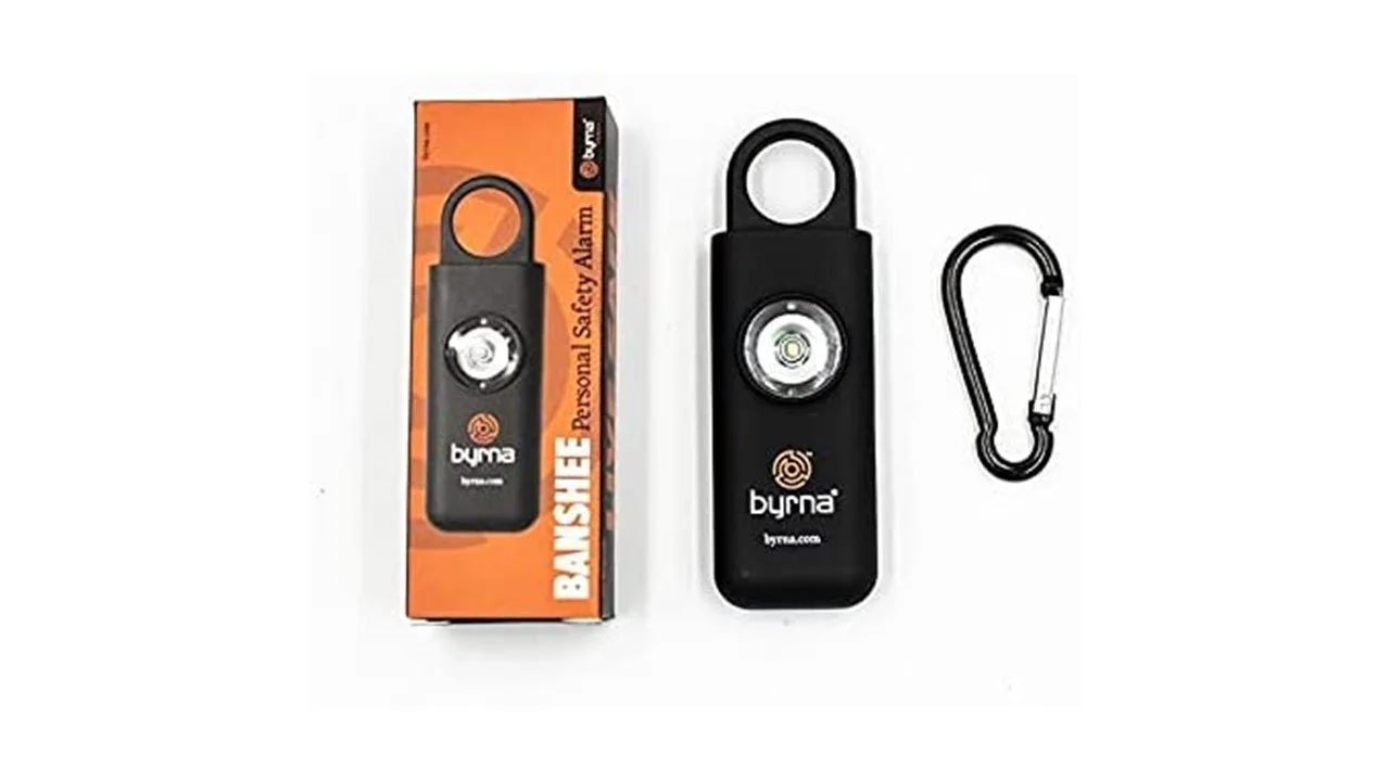 Byrna personal safety alarm with packaging, a black carabiner, and an orange box labeled "Banshee". The device features a circular button and loop at the top.
