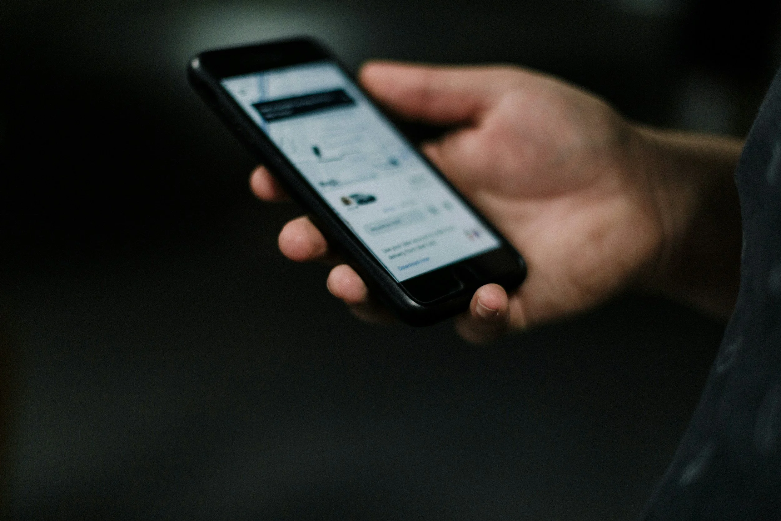 A person holding a smartphone with a social media feed visible on the screen.