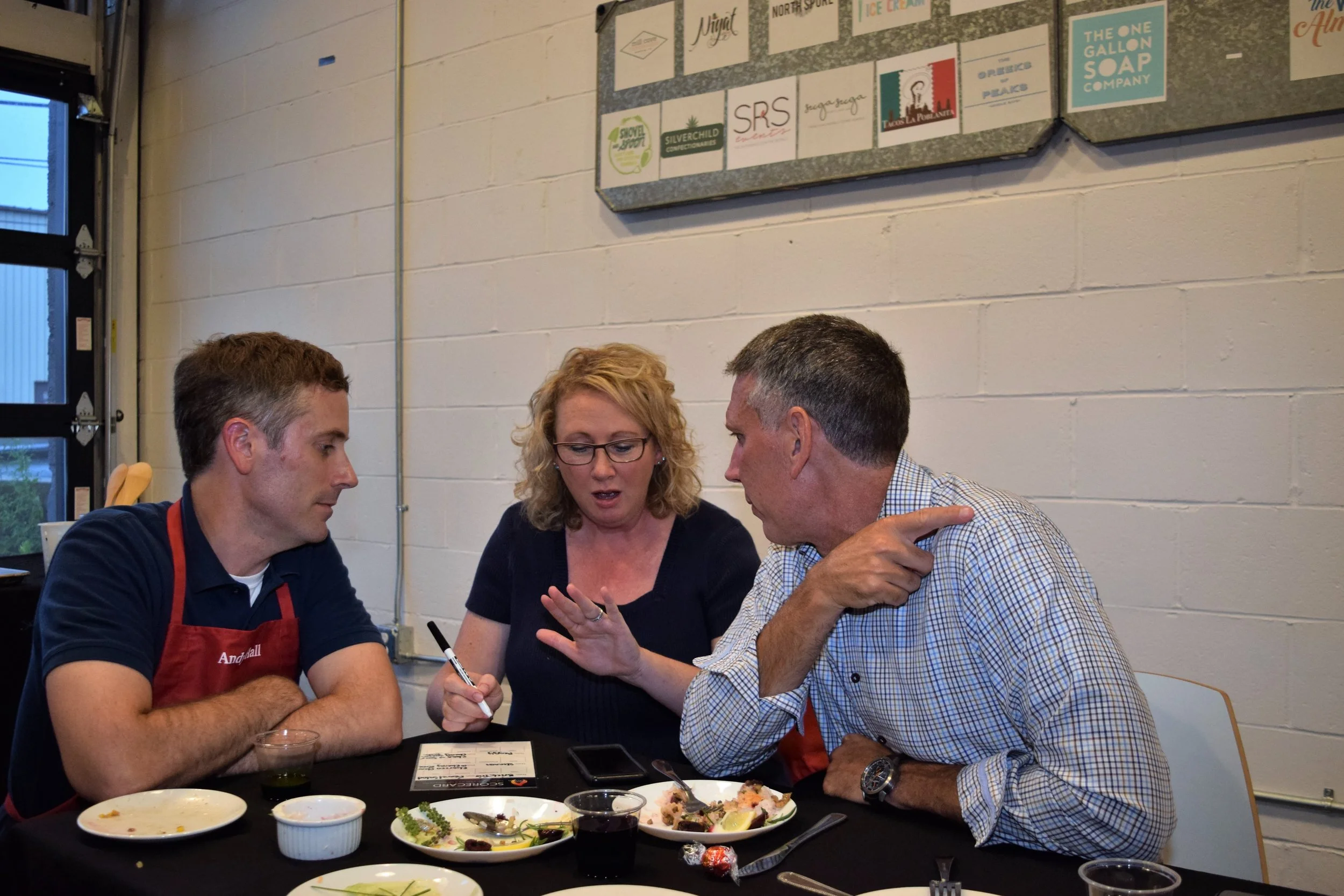 Member of Team Shake ‘N Bake collaboratively scoring their competitors’ dishes