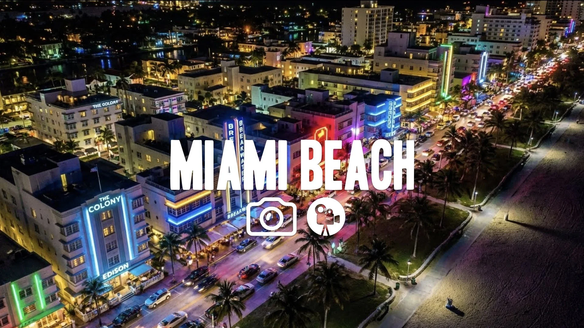 Helicopter aerial shot sweeping across the Miami Beach strip, colorful neon signs, high-key lighting, no music.