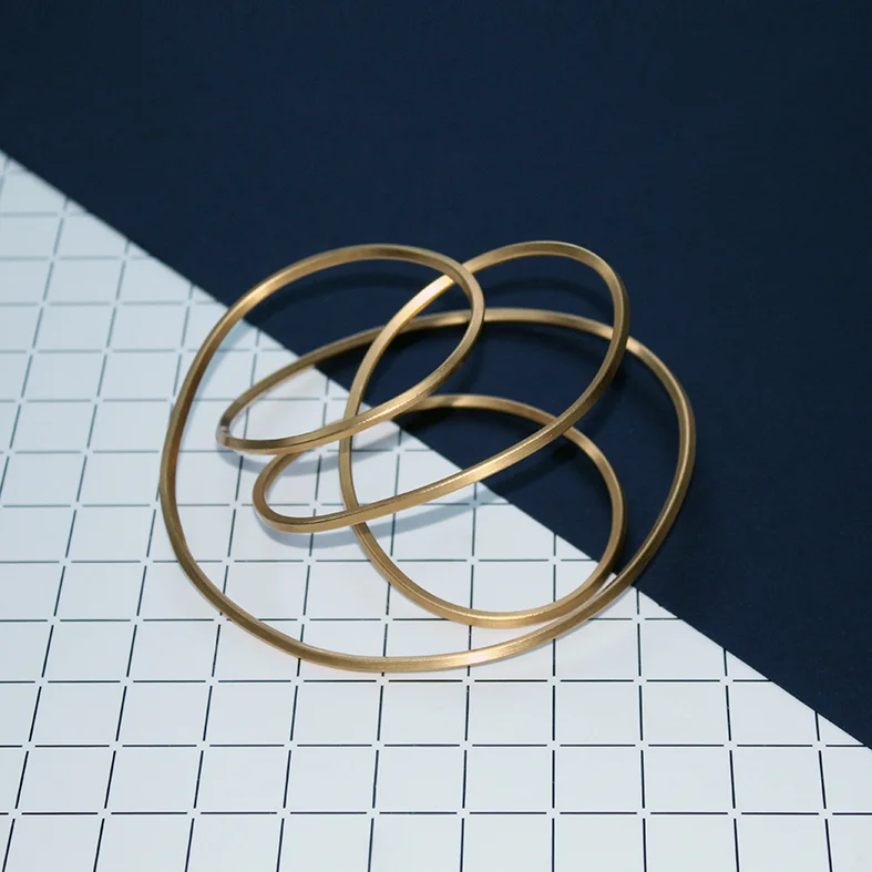 INFINITY BANGLES (LARGE AND SMALL SIZES SHOWN INTERLOCKING) 22 CARAT GOLD-PLATED BRASS: LARGE INFINITY BANGLE £320 SMALL INFINITY BANGLE £280 ALSO AVAILABLE IN BRASS: LARGE BRASS INFINITY BANGLE £150 SMALL BRASS INFINITY BANGLE £120