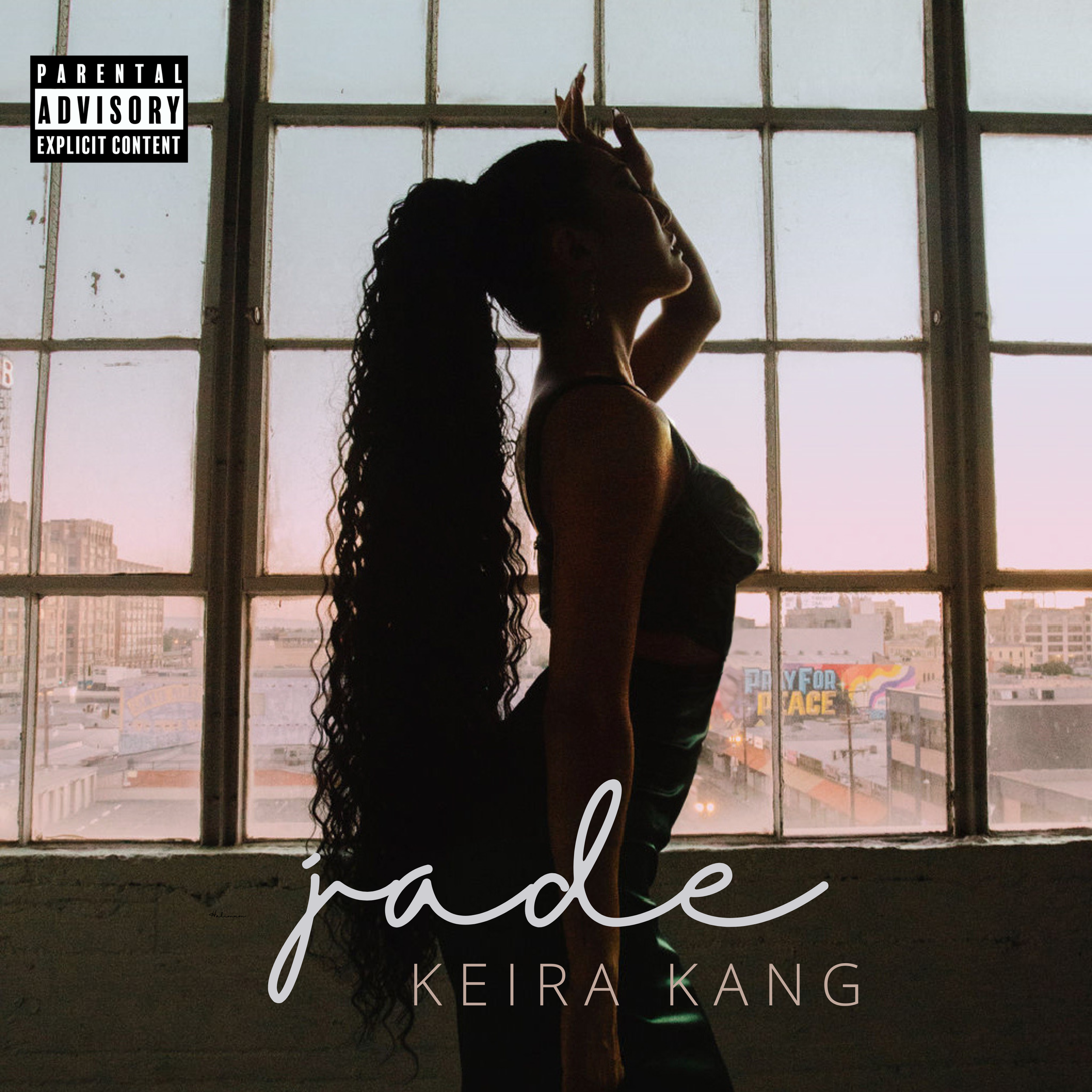 The silhouette of a woman with long curly hair by the windows during sunset golden hour in downtown Los Angeles.