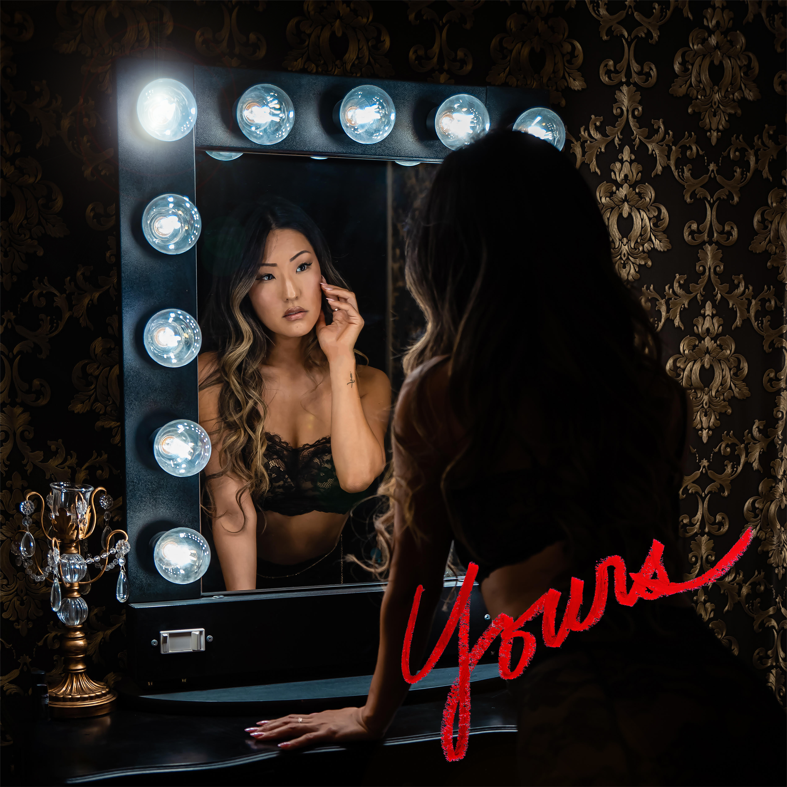 A woman dressed in lingerie staring at herself in the vanity mirror while reflecting in a dark hotel room.