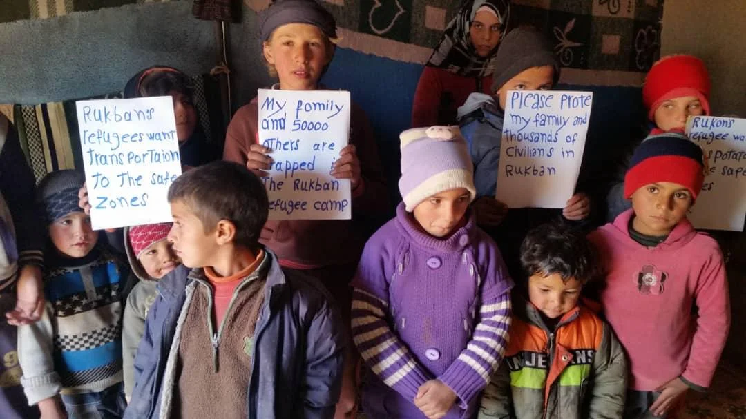 Kids in Rukban hold signs pleading for protection