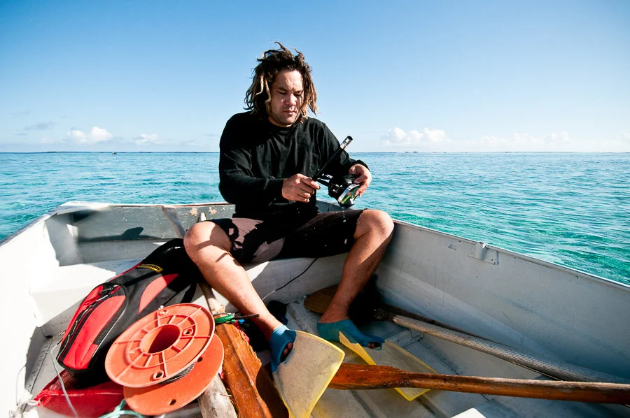 Spear fisherman putting on his flippers, snorkel and mask on a dingy, Aitutaki, Cook Islands.