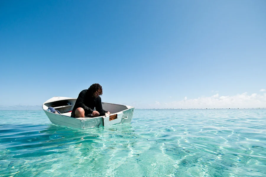 Spear fisherman gutting and cleaning freshly caught reef fish, Aitutaki, Cook Islands.