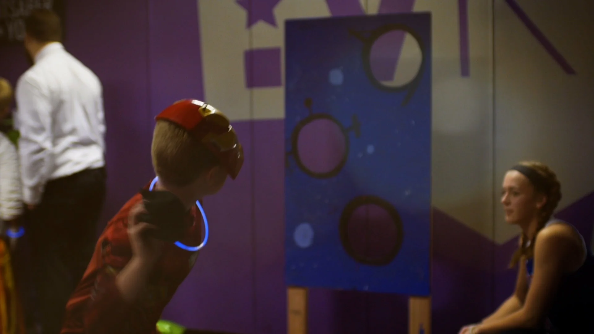 Boy dressed as Iron Man enjoys a beanbag toss carnival game