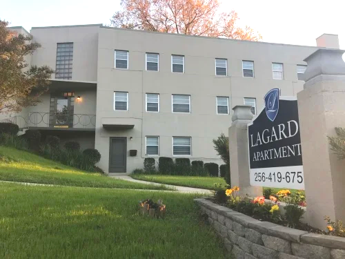 Exterior view of Lagard Apartments with a sign displaying contact information.