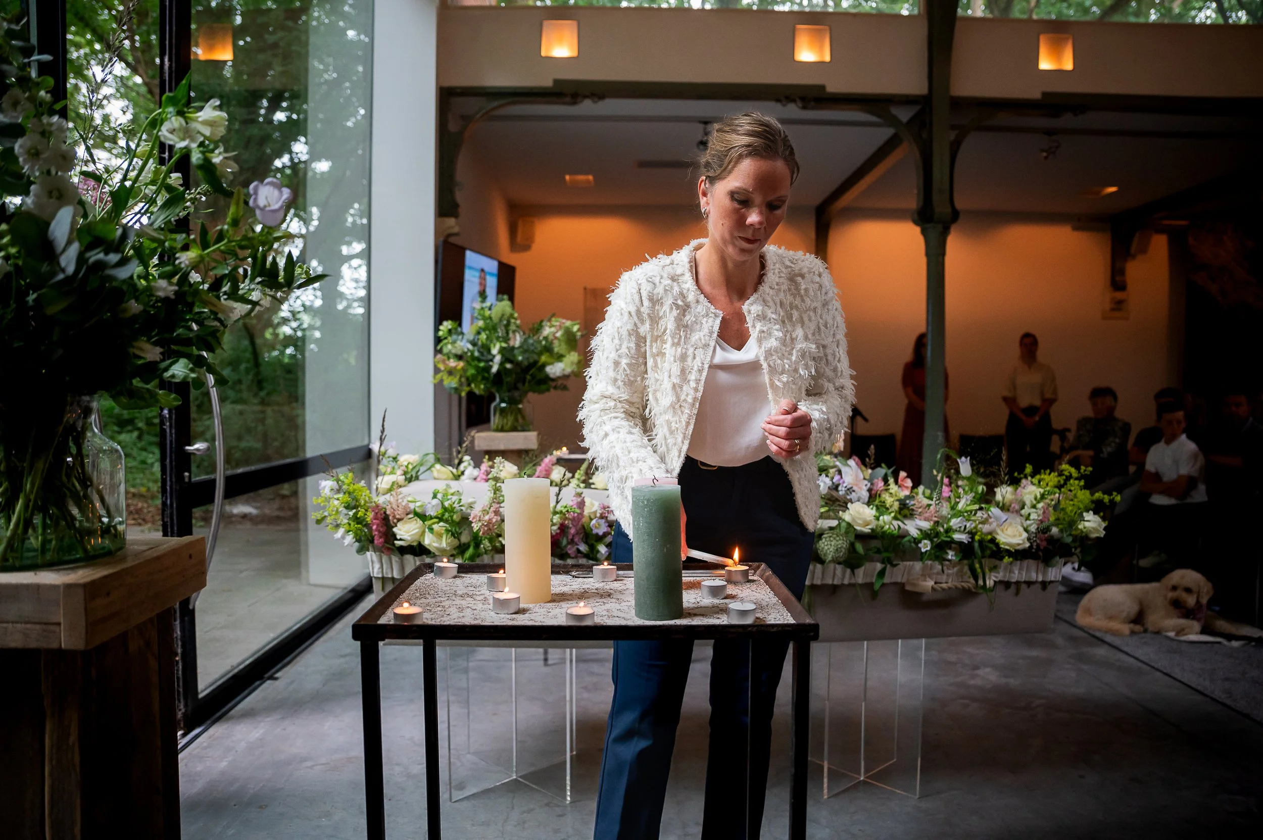 Patricia steekt kaarsjes aan bij een afscheid. Troosthond Ruby op de achtergrond