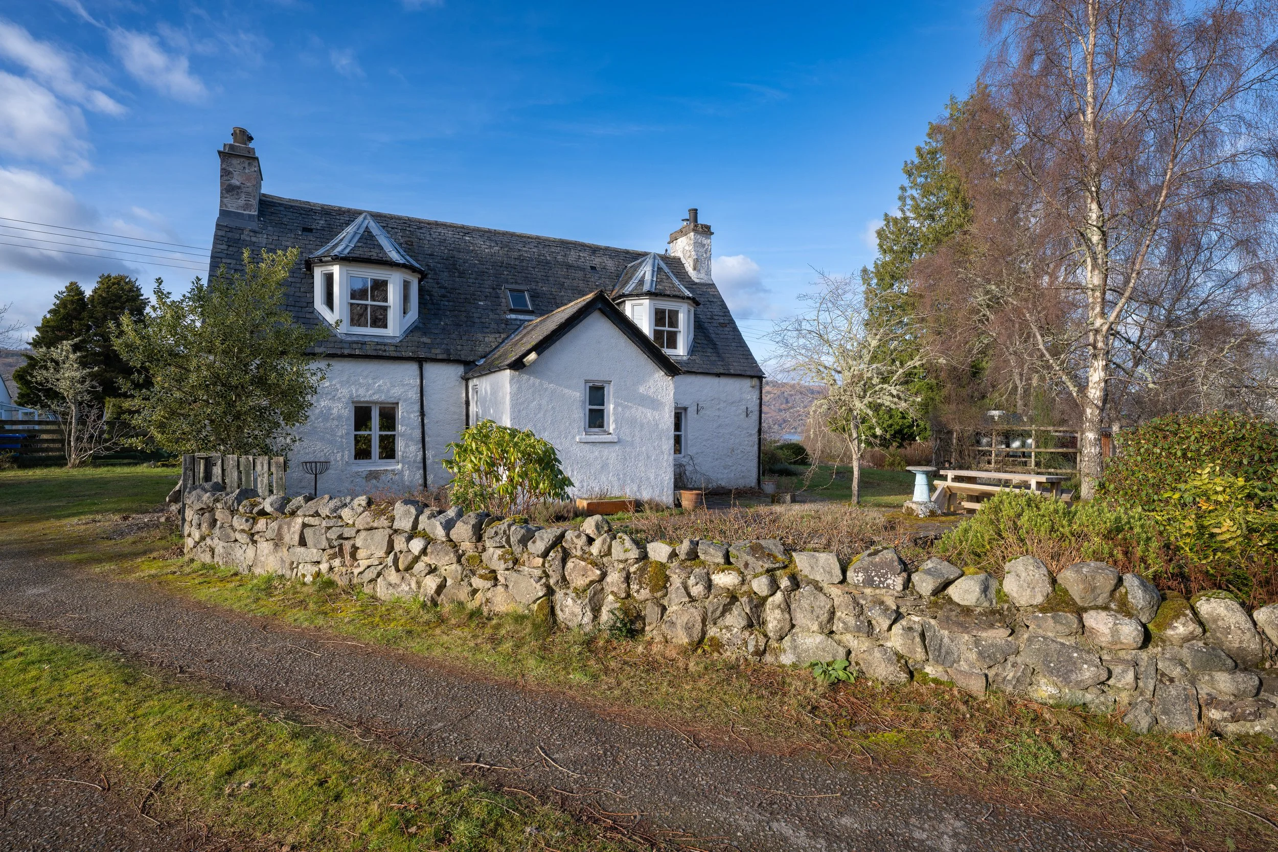 Exterior photograph of a white Highland cottage