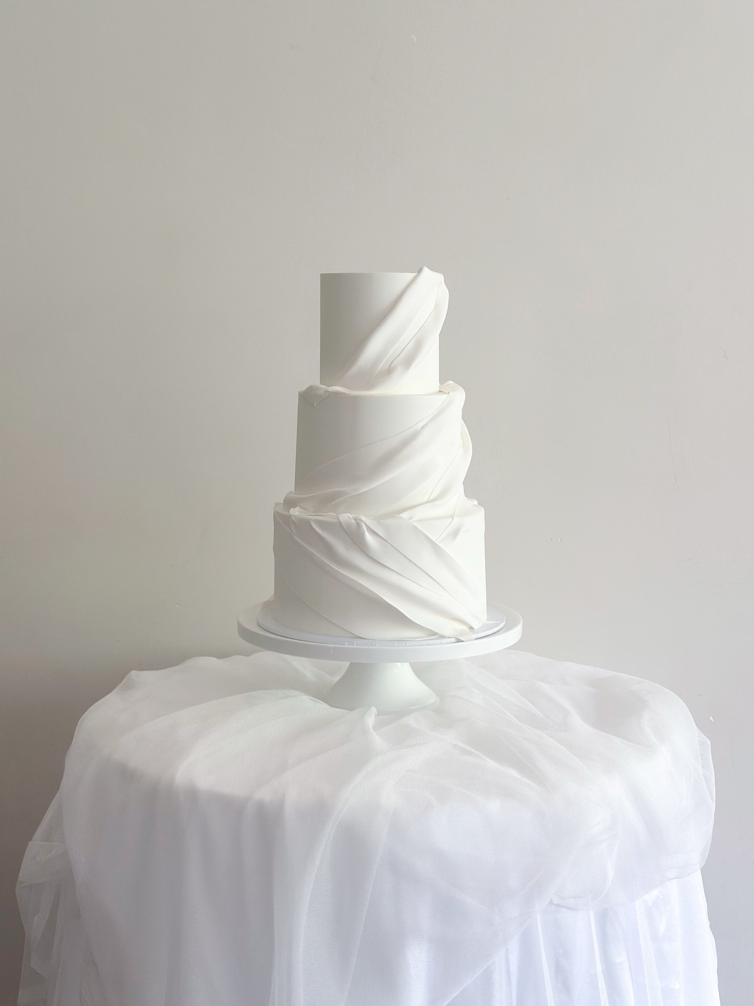Samantha &amp; James 🤍
Soft draping ruffles on a pretty April afternoon. 
Three tiers of Orange, Passionfruit &amp; Elderflower, one of our most popular flavours. Light, fresh, and perfect for the moment. ✨

With;
@coastportbeach 
@jemweddings_ 
@si