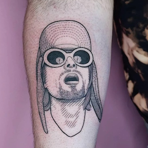 Line art tattoo of a person wearing large sunglasses and a beanie, with a surprised expression.