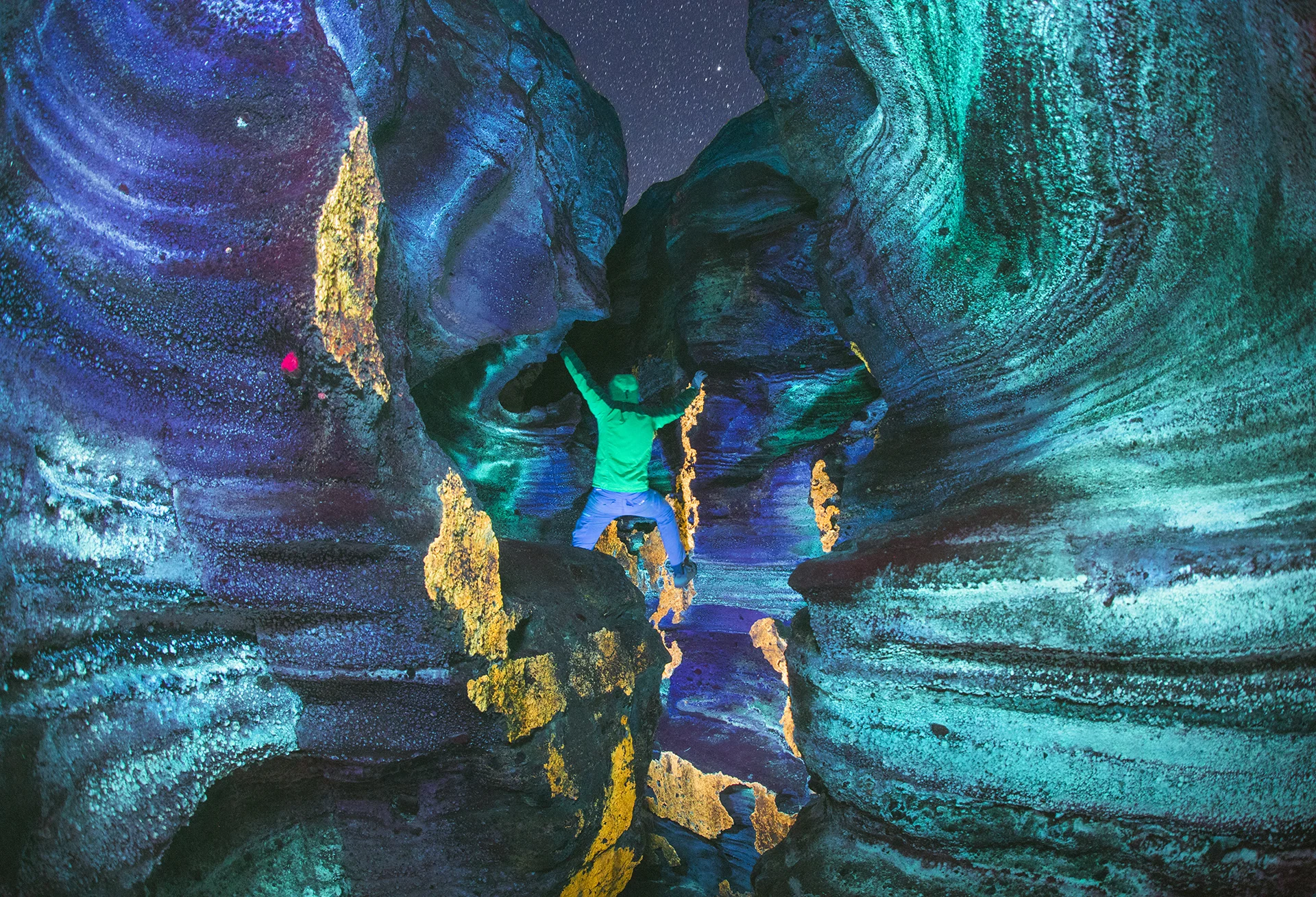 Self portrait in a volcanic fissure near Mono Lake. I took this image at night under short wave ultraviolet illumination, which causes certain minerals to emit a variety of colors.