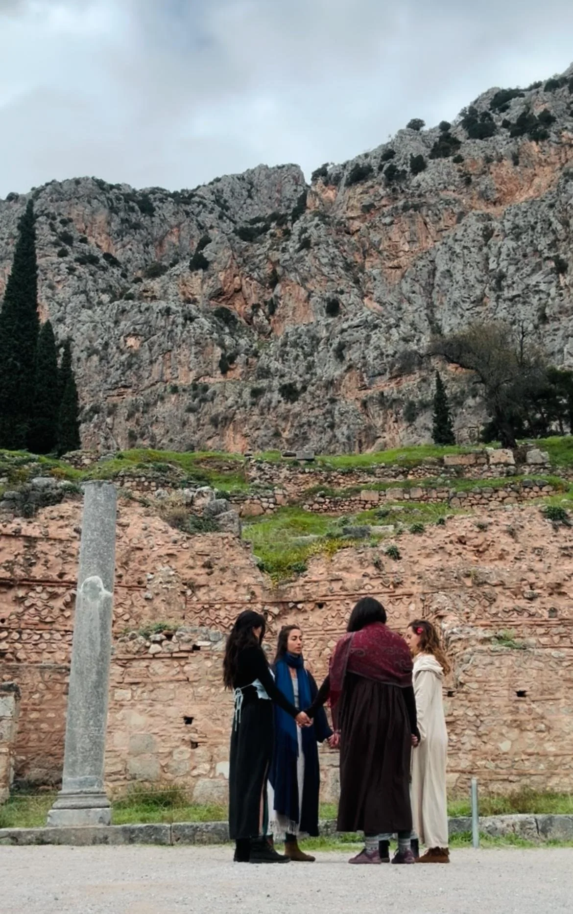  women praying in a circle at the oracle temple of delphi 