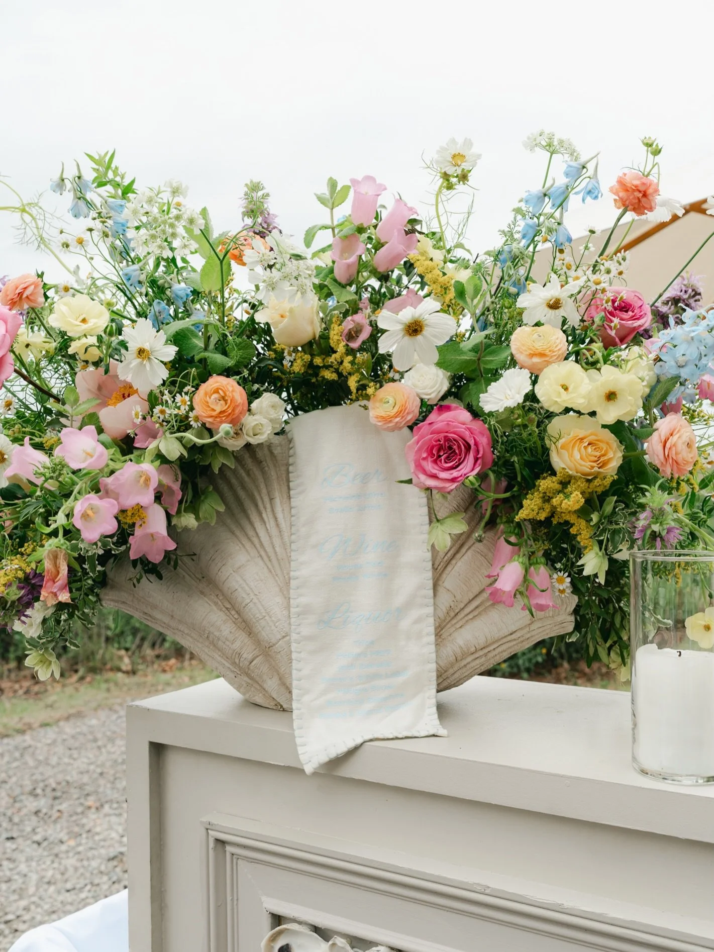 Maddie and Caden&rsquo;s wedding day, brought to life by every color spring had to offer. Blush peonies, sky blue delphinium, and buttery ranunculus spilling over every surface. We were lucky to dress the ceremony, the reception, even the bar in bloo