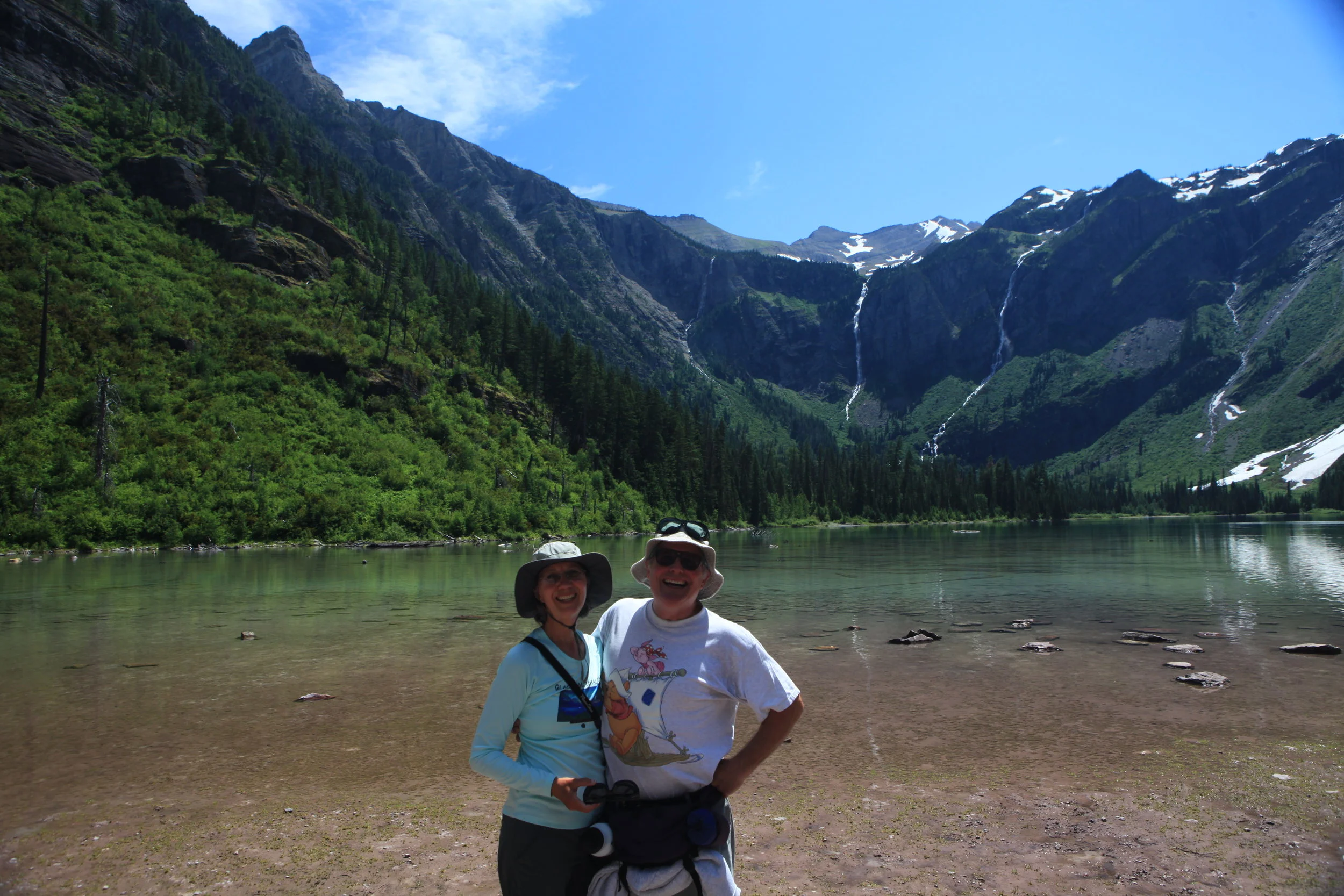 Me enjoying life again. My husband joins me at Avalanche Lake in Glacier NP. This shows my adapted hiking hat with flaps up.
