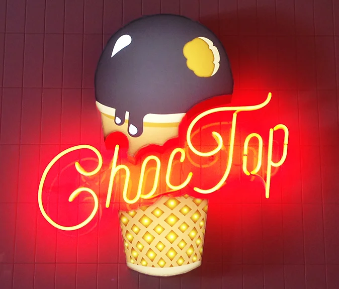 CHOC TOP NEON SIGN The center piece for the snacks area was the Choc Top neon sign. A fabricated acrylic ice-cream cone with digitally printed detail and internally illuminated with LEDS. Open red neon letters.