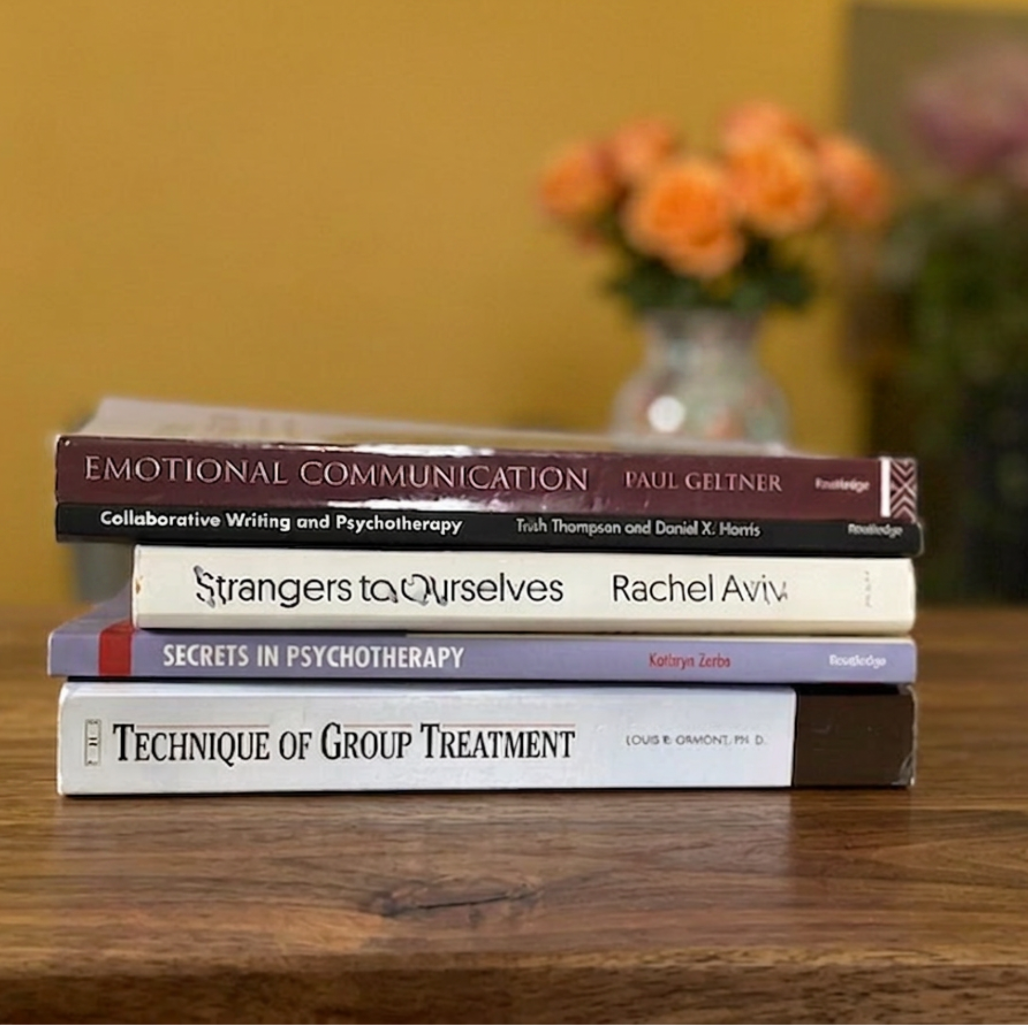 Stack of five books on psychotherapeutic techniques resting on a wooden surface.