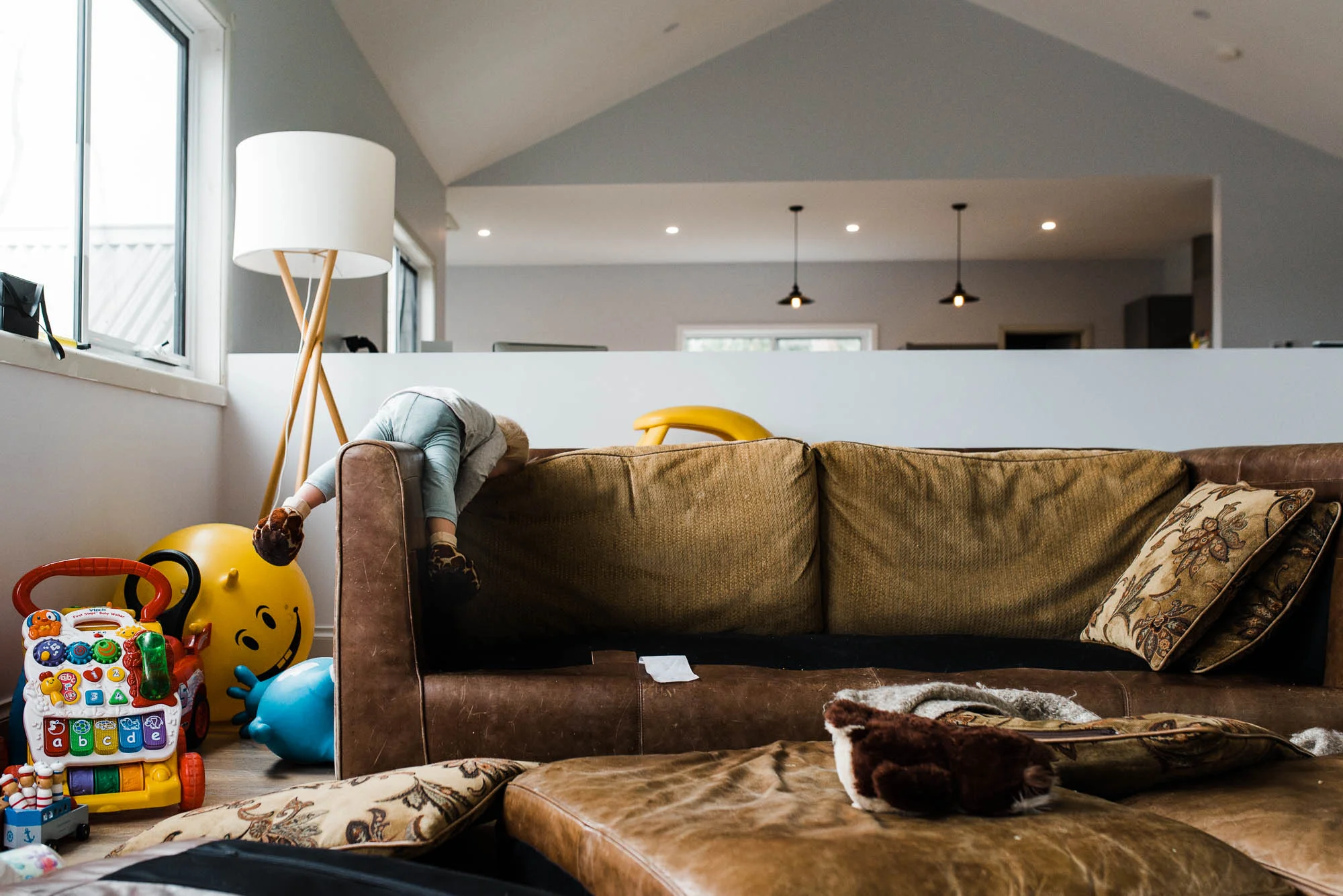 child_laying_on_arm_of_sofa_with_all_cushions_removed.jpg