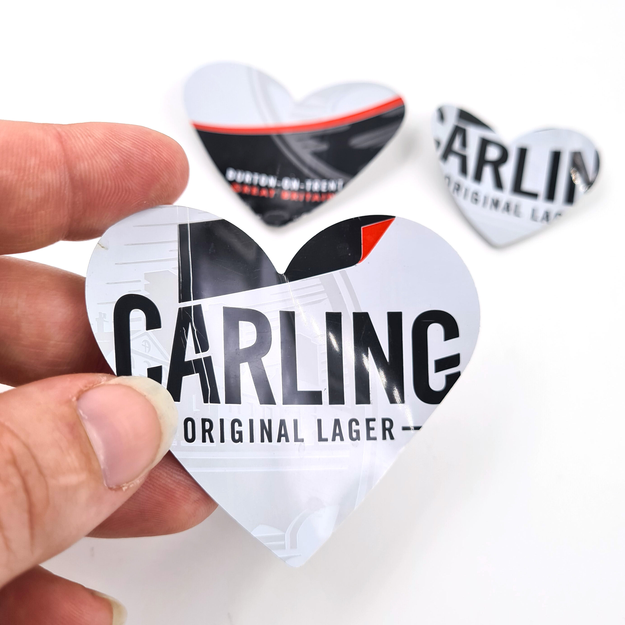 Red black and white Carling Heart Can Magnets holding