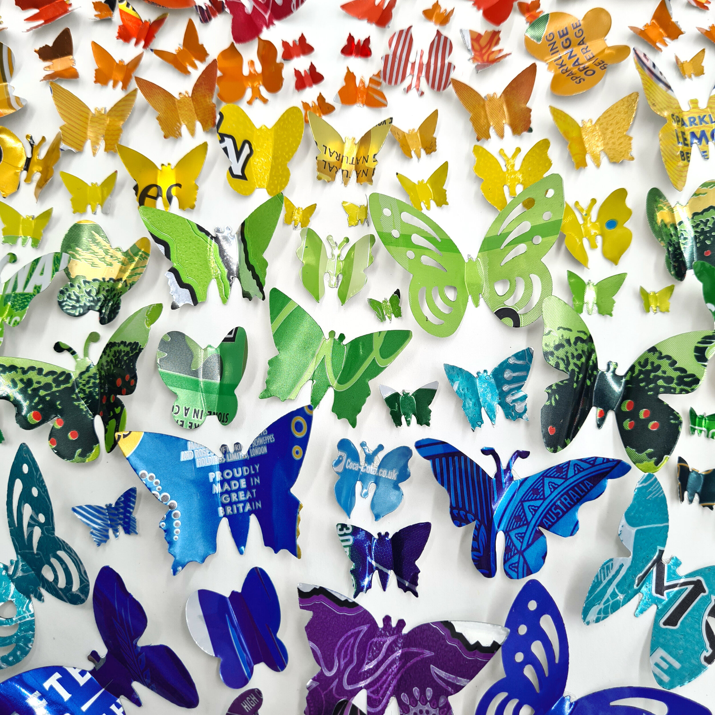 Close up of rainbow butterflies cut from upcycled drinks cans