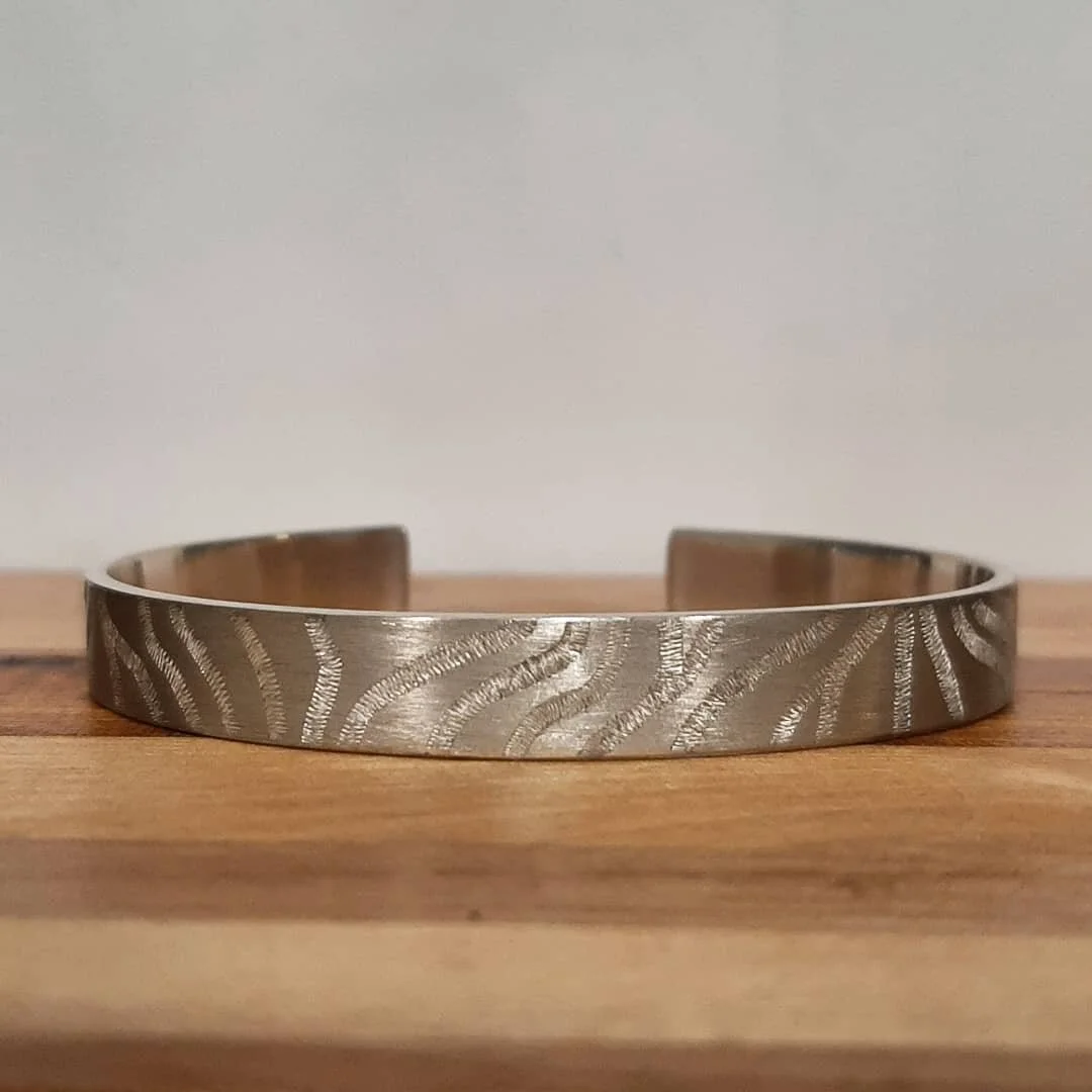 Engraved patterned cuff made out of Argentium Silver(.935) which is a recycled alloy that is more tarnish resistant than traditional Sterling (.925). I think it has a warmer, softer look that resembles fine silver(.999), but is more durable than eith
